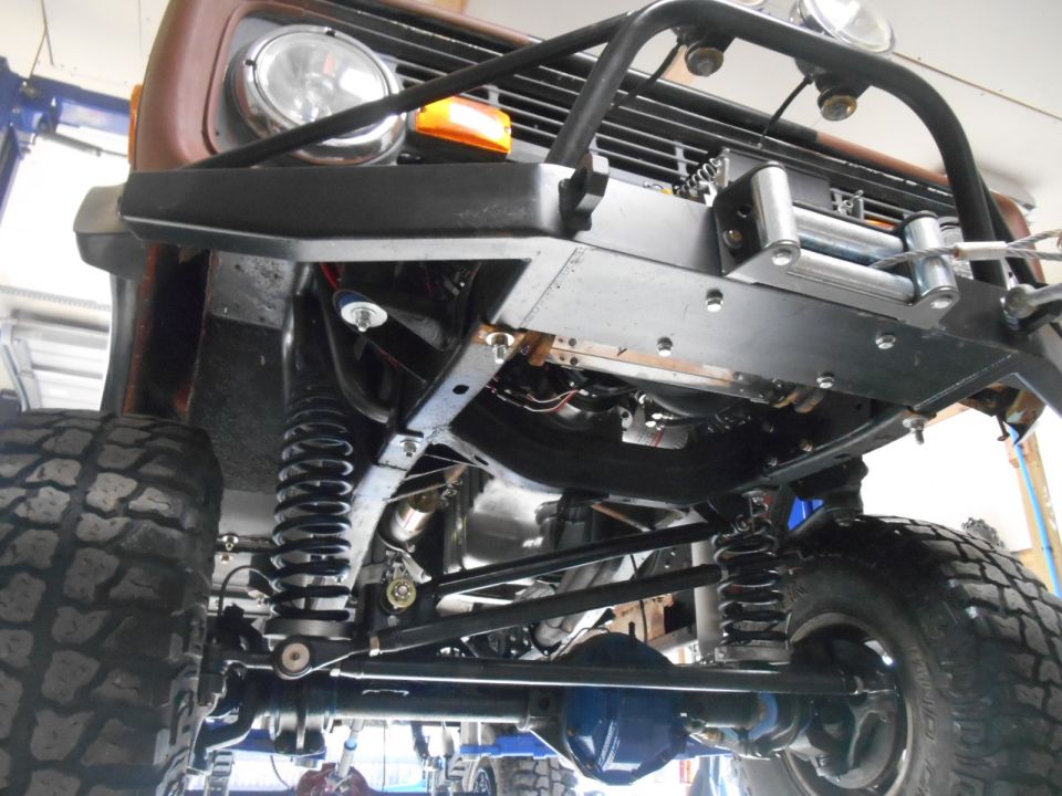 Underside of a modified vintage Ford Bronco showing suspension, winch, and custom bumper.