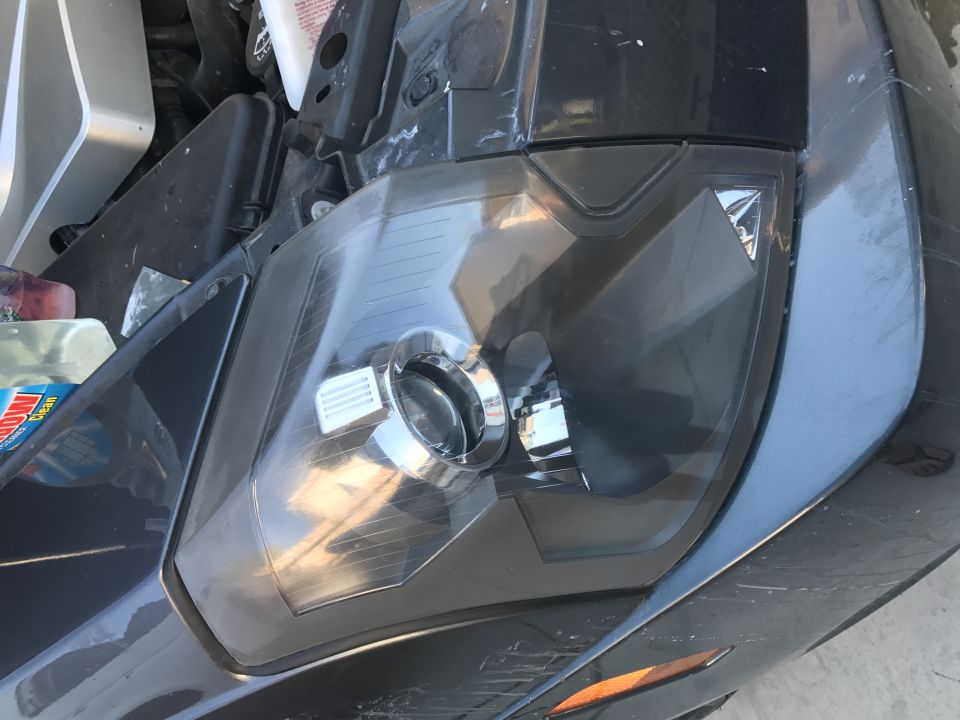 Driver's side headlight of a dark Cadillac CTS
