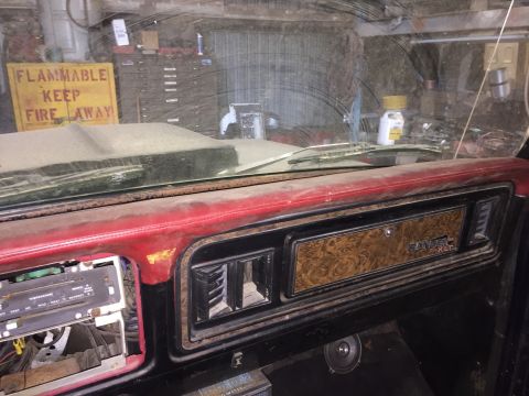 1979 Ford Bronco - Interior view of a dusty dashboard in a vintage Ford truck or SUV, featuring a wood-grain trim panel with 'RANGER XLT' badging and a red vi…
