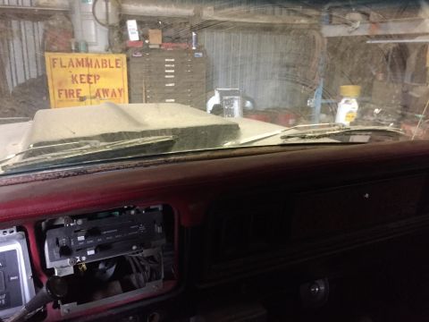 1979 Ford Bronco - Interior view of a vintage vehicle's dashboard and windshield, showing a dusty hood scoop and a "Flammable Keep Fire Away" sign visible thr…