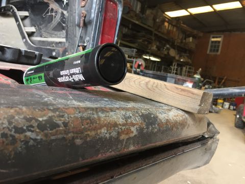 1979 Ford Bronco - A tube of Multi-Purpose Lithium Grease rests on the rusted edge of a vehicle's body panel, possibly a tailgate, in a workshop setting. A wo…