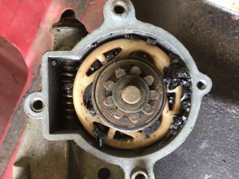 1979 Ford Bronco - A close-up view of a damaged starter motor with a broken gear and debris. The metal housing is visible with mounting holes.