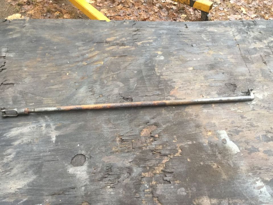 Rusty metal rod with clevis end and bent end on weathered wood