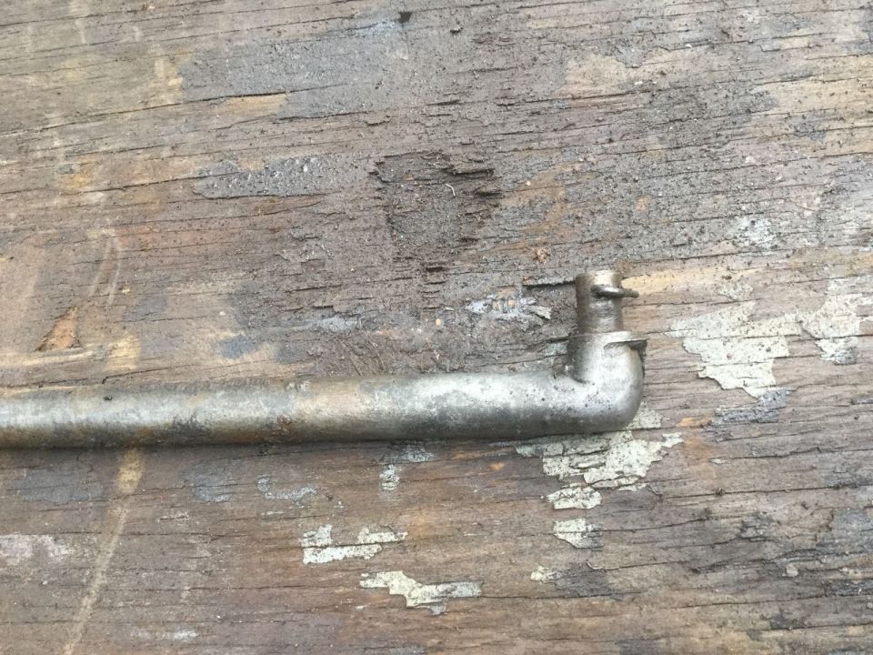 Metal rod with bent end and pin on weathered wood