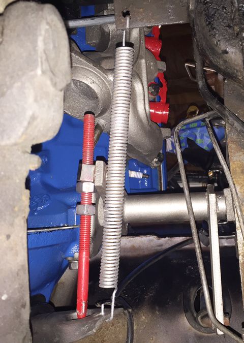 1978 Ford Bronco - A close-up view of engine components, including a bright blue engine block, a silver spring, and a red threaded rod with nuts. The scene ap…