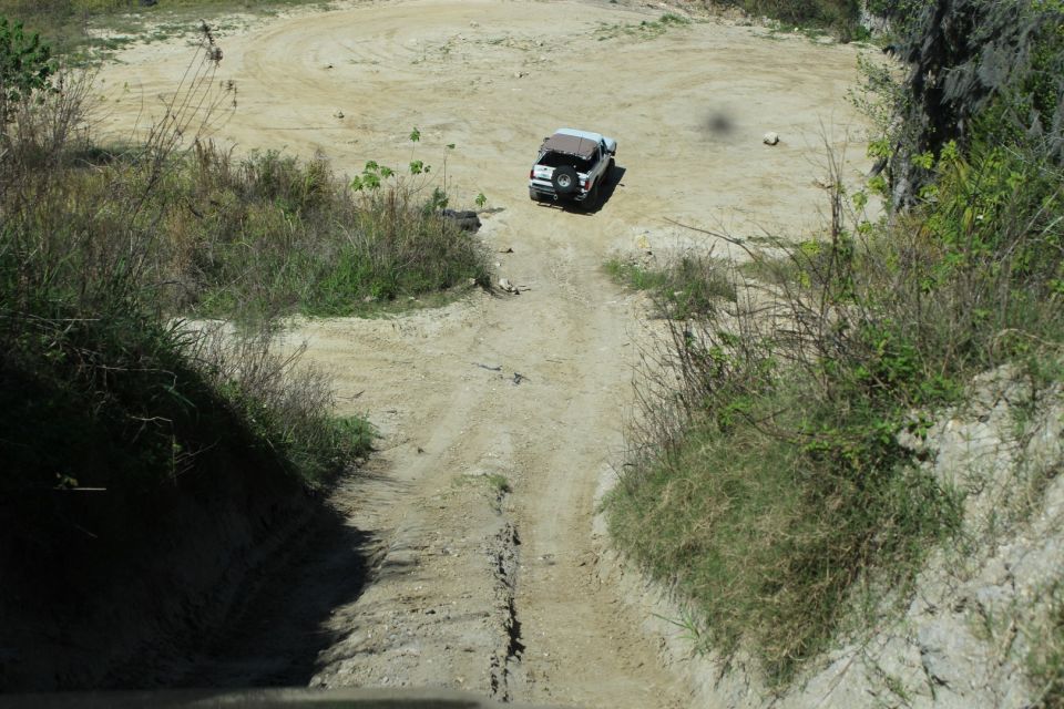 White 1992 Ford Bronco driving up a dirt track in a quarry.
