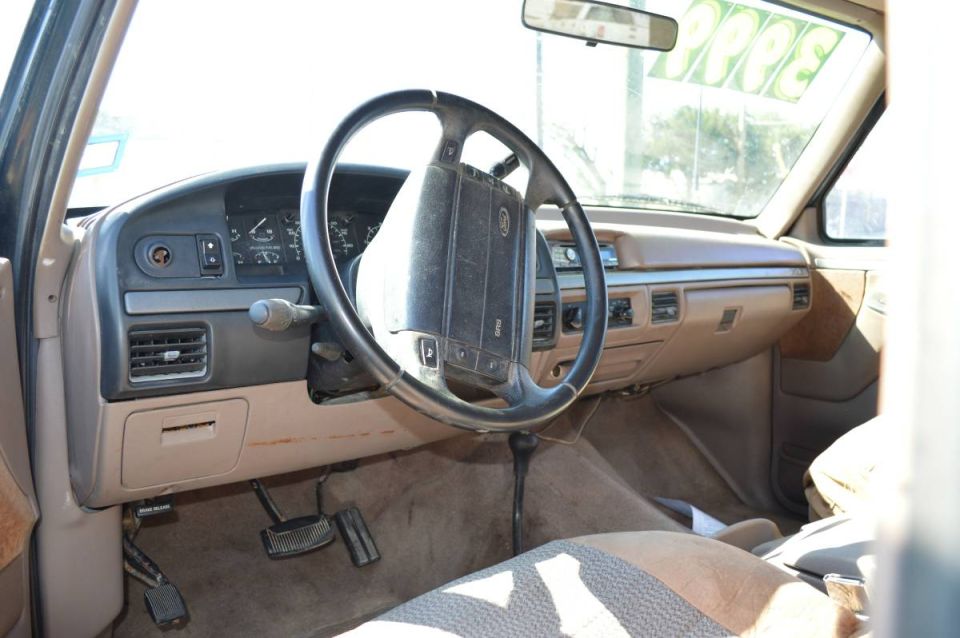 Interior of a 1995 Ford Bronco showing the dashboard, steering wheel, and manual shifter.