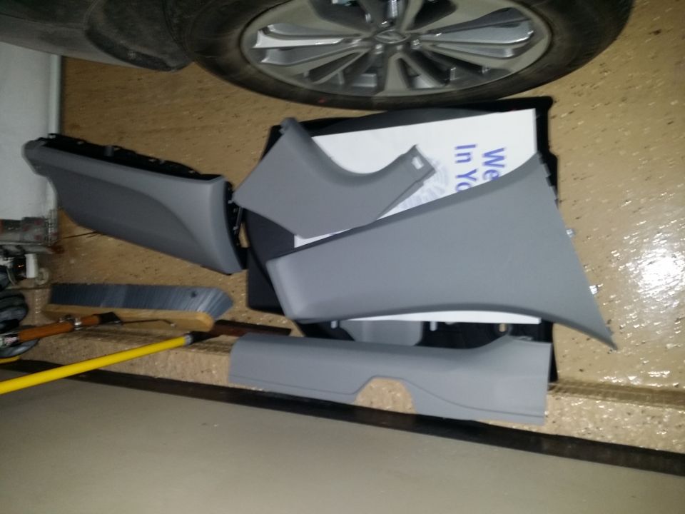 Gray plastic car interior trim pieces on a garage floor.