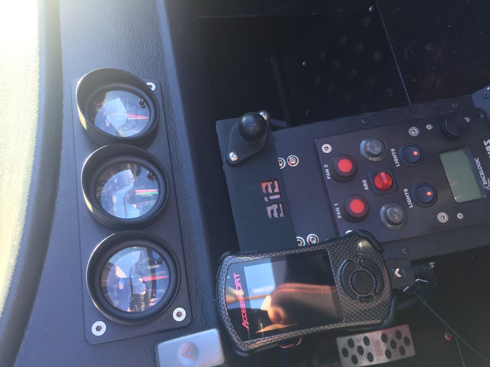 Car dashboard with gauges, control unit, and a carbon fiber device.