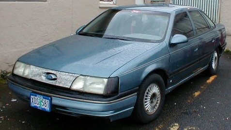 1986 Ford Taurus - This blue sedan is a 1986 Ford Taurus, seen from the front three-quarter angle.