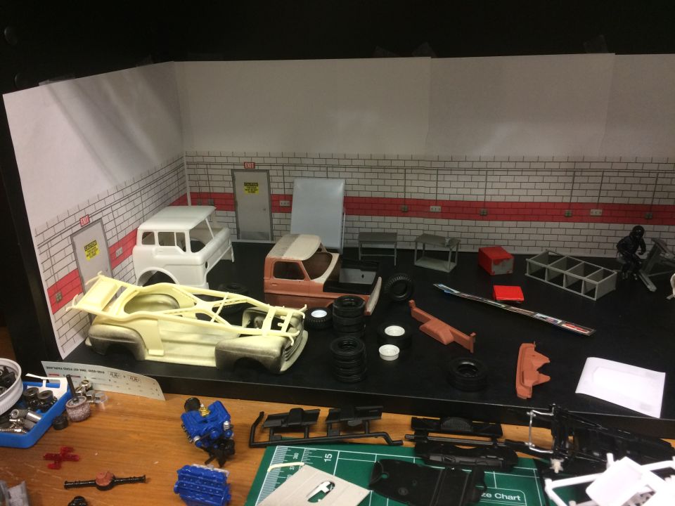Model car garage scene with unassembled parts and partially built model trucks.