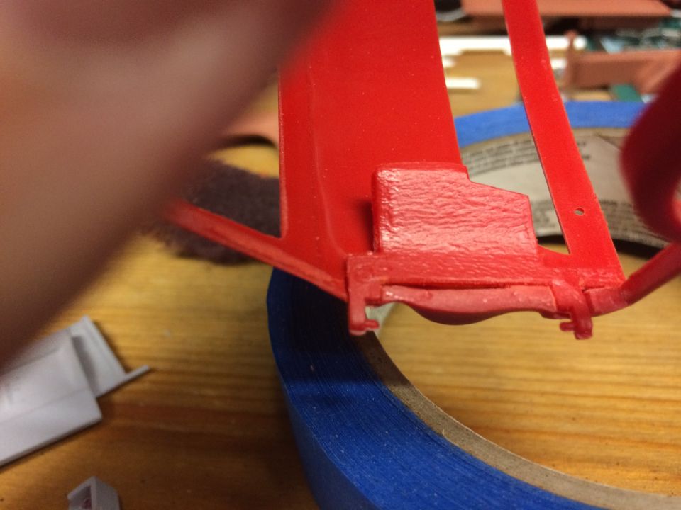 Red plastic model part with blue tape