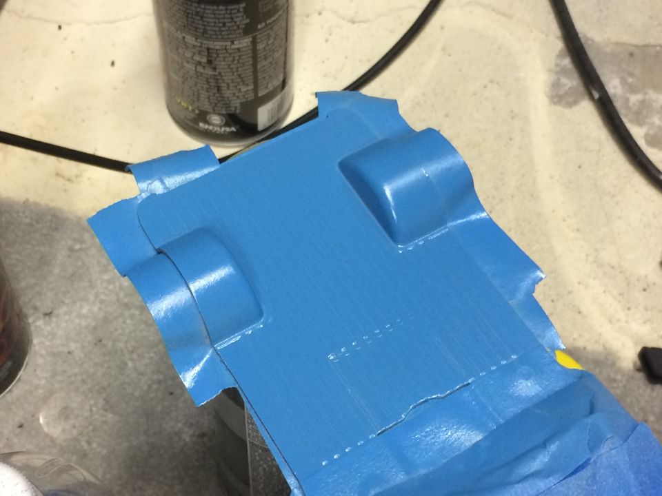 Blue car part with blue masking tape applied to edges.