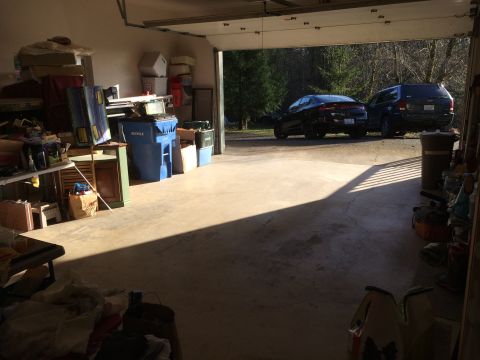 1964 Ford Fairlane - A dark colored sedan and a dark colored SUV are parked in a garage with the door open, facing outwards. The garage is cluttered with variou…