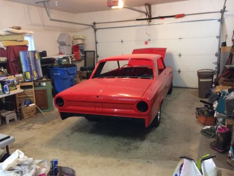 1964 Ford Fairlane - A red, unfinished 1964 Ford Fairlane is parked in a cluttered garage with the hood and trunk open. The car is missing its headlights, grill…