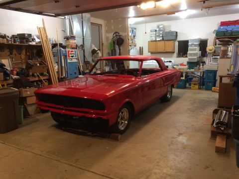 1964 Ford Fairlane - A red 1964 Ford Fairlane coupe sits in a garage, appearing to be undergoing restoration or modification.