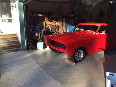 1964 Ford Fairlane - A red coupe sits in a garage, appearing to be in the process of restoration with its front grille removed.