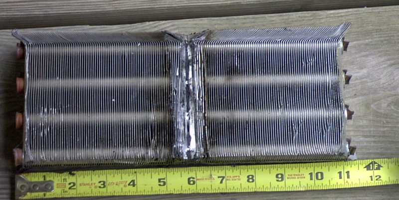 Damaged car radiator core with fins and tubes, measured with a tape measure