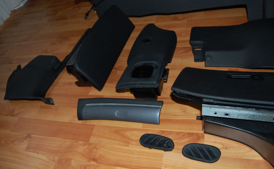 Black interior car parts laid out on a wooden floor