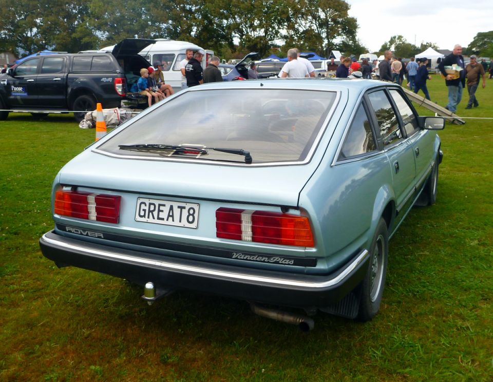 Light blue Rover Vanden Plas, rear view, license plate GREAT8, parked on grass.