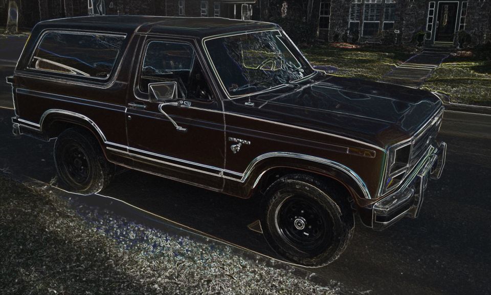 Edge-glow filtered photo of a dark 1980s Ford Bronco SUV parked on a street, 3/4 front view
