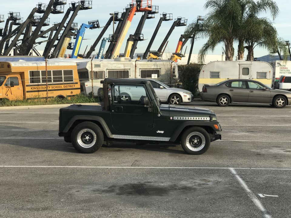 Black Jeep Wrangler pickup conversion parked in a paved lot