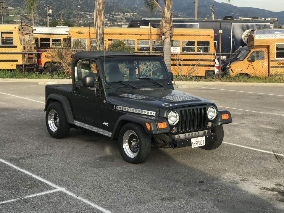 Black Jeep Wrangler pickup conversion parked outdoors near food trucks
