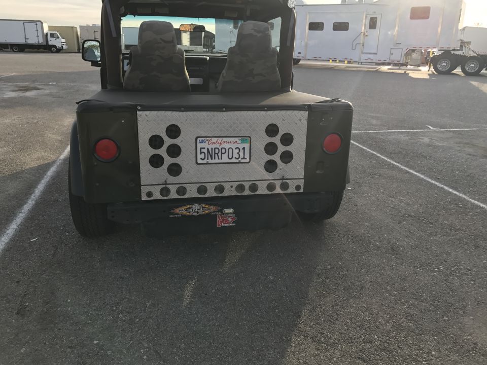Rear view of a green Jeep Wrangler pickup conversion with California plate