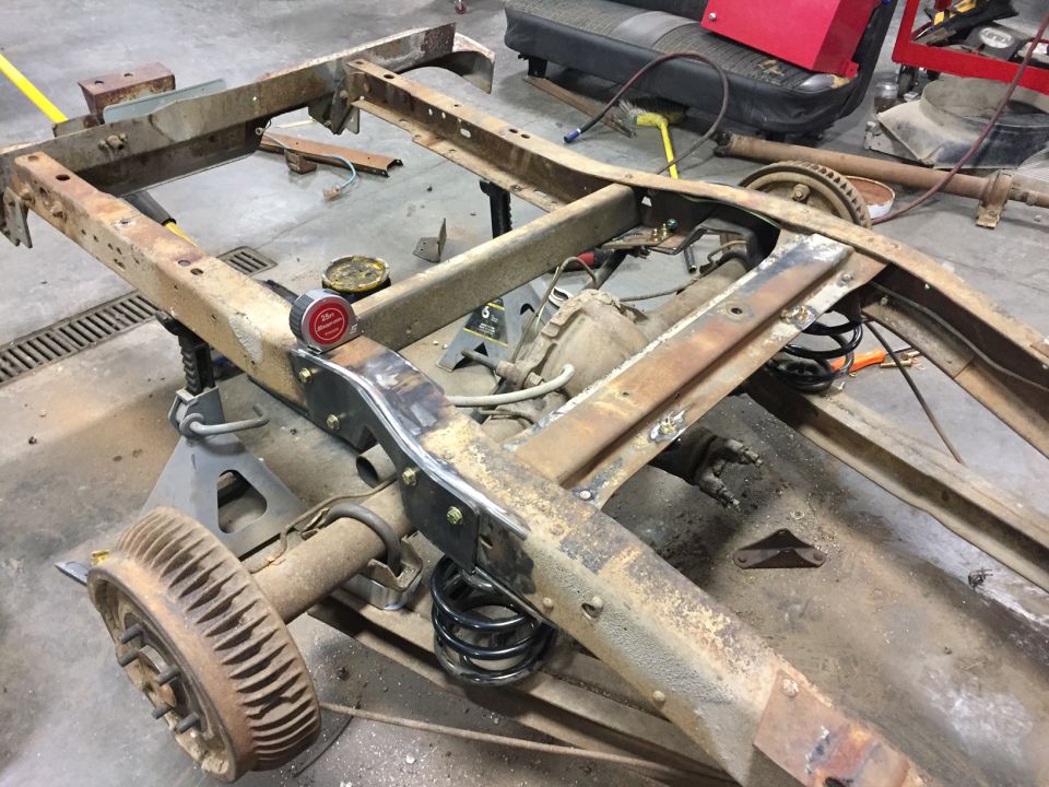 Rusty truck/SUV frame on jack stands with modifications in progress.