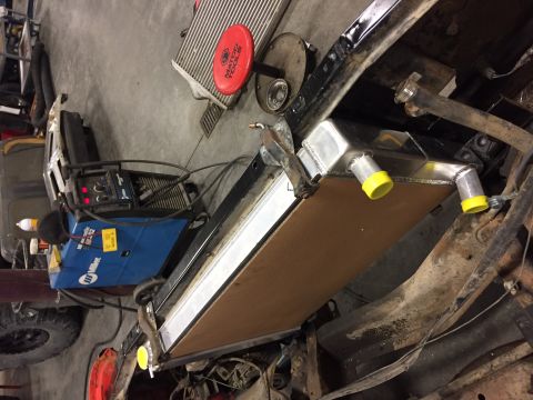 1984 Ford Bronco - A new aluminum radiator is being installed in the chassis of a classic vehicle, possibly a Ford Bronco, with a Miller welding machine visib…