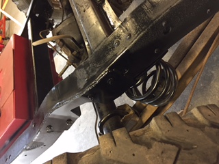 1984 Ford Bronco - A close-up view of the black painted frame of a 1984 Ford Bronco, showing a coil spring and part of a large tire. The frame appears to be u…