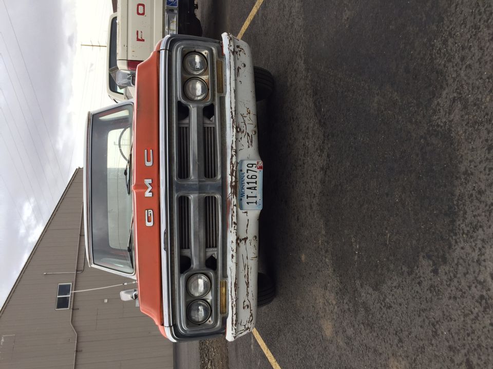 Front view of an orange and white GMC pickup truck with a Montana license plate.