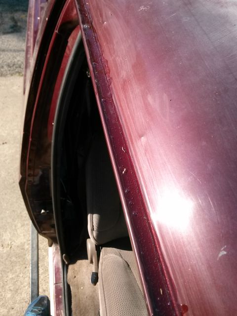 1996 Ford Bronco - Close-up of the driver's side door jamb on a maroon vehicle, showing some residue along the edge and the interior seat. The door is open, r…