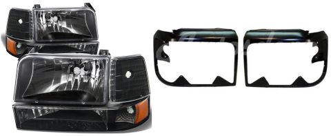 1996 Ford Bronco - A pair of black projector headlights and a pair of black headlight bezels are displayed against a white background. The headlights feature…
