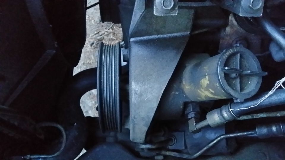 Off comes the pulley, you do need a special tool for this. Behind the pulley are 3 17mm bolts (11/16 will work in a pinch) that need to come out. Also the pressure hose fitting is 18mm (I highly suggest taking that out before pulling the bolts on the face out); there is a pressure valve that will keep fluid inside the reservoir so you will not make a mess taking this out. After that it's pull off the return hose (which will make a mess if you do not evacuate the reservoir) and the pump is off.