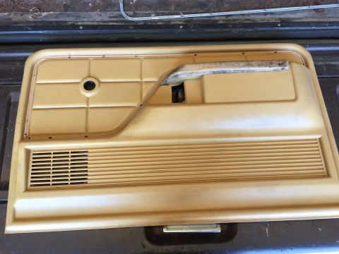 1979 Ford Bronco - A tan-colored plastic door panel with a speaker grille and a pull handle is shown from a top-down perspective. The panel appears to be from…