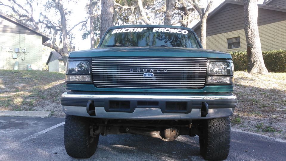 1996 Ford Bronco front view, dark teal, chrome grille, "BUCKIN' BRONCO" windshield banner
