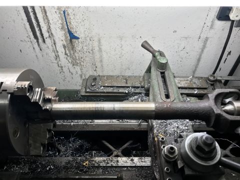 1996 Ford Bronco - A metal shaft is being worked on by a lathe in a workshop environment.