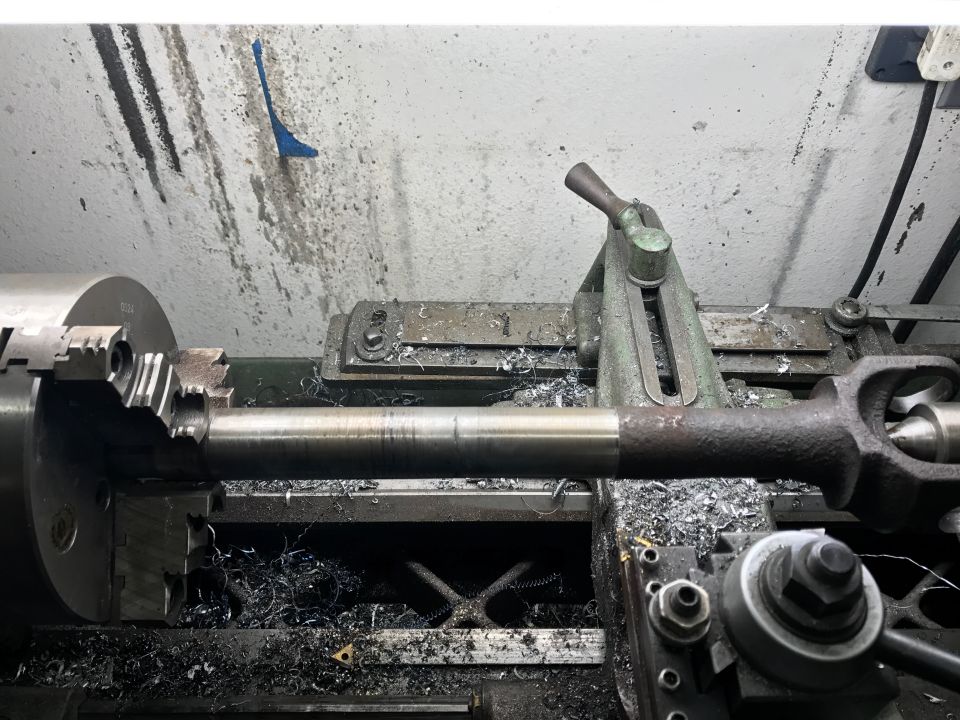 Metal shaft being machined on a lathe, with metal shavings scattered around