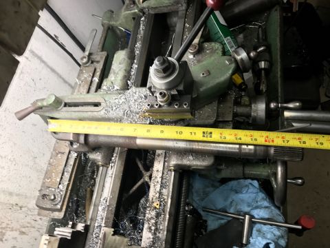 1996 Ford Bronco - A metal shaft is being machined on a lathe, with a tape measure indicating its length.