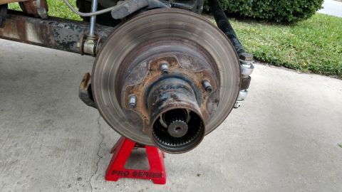 1992 Ford Bronco - The vehicle's front brake rotor and hub assembly are shown, supported by a red jack stand.