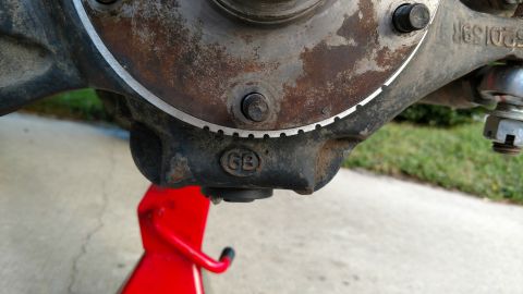 1992 Ford Bronco - A close-up view of a vehicle's spindle assembly, marked with a 'GB' emblem and resting on a red jack.