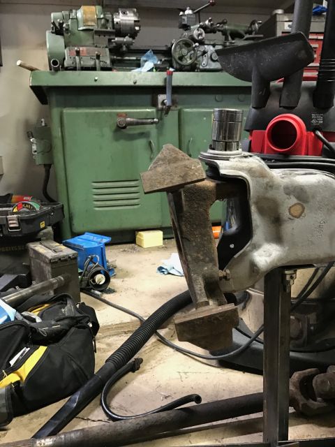 1996 Ford Bronco - A vehicle suspension component is secured in a vise, with industrial machinery visible in the background.