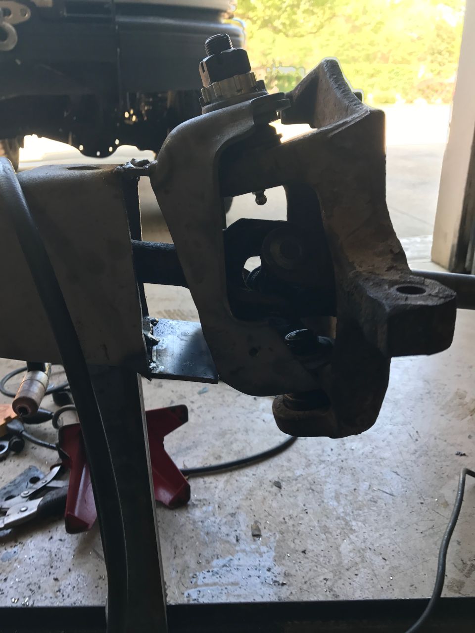 Close-up of a vehicle's front suspension knuckle assembly, possibly being worked on in a garage