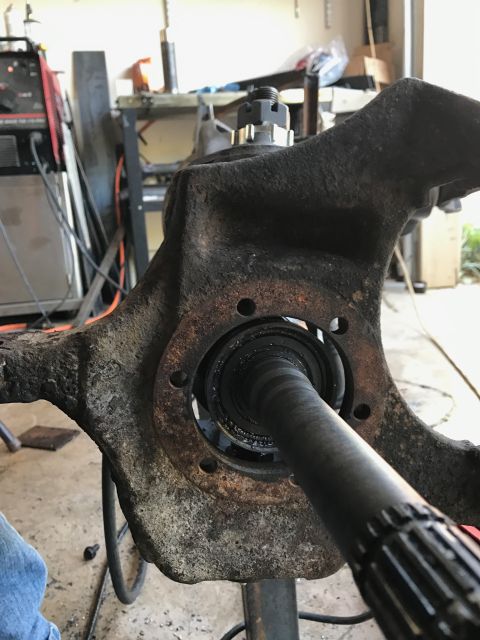 1996 Ford Bronco - Close-up of a greasy, worn vehicle spindle and axle shaft assembly.
