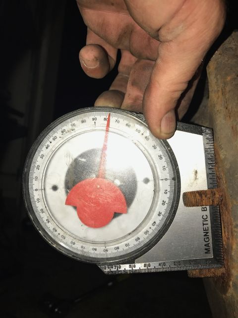 1996 Ford Bronco - A mechanic uses an angle gauge to measure a rusty metal component, possibly for vehicle repair or modification.