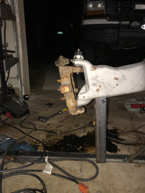 1996 Ford Bronco - A close-up view of a vehicle's suspension components, likely from a 1996 Ford Bronco, being worked on in a garage. The scene shows rusty an…