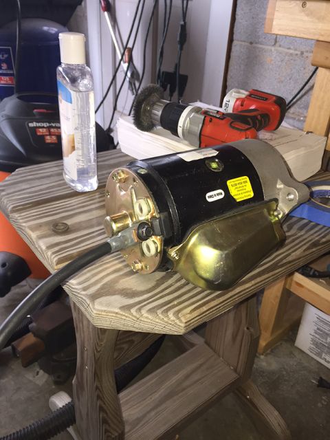 1978 Ford Bronco - A black and gold starter motor is displayed on a wooden table, with a red cordless drill and a bottle of hand sanitizer in the background.