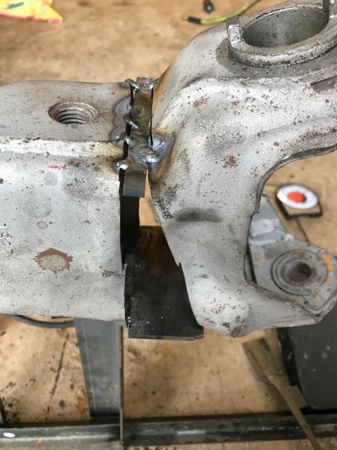 1996 Ford Bronco - A close-up view shows a metal part that has been welded together, with visible weld beads and some rust on the surface. The part is held in…