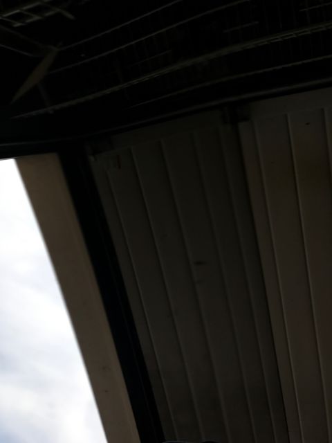 1996 Ford Bronco - The underside of a dark-colored roof structure is visible, with a bright sky peeking through an opening on the left. A section of a light-c…